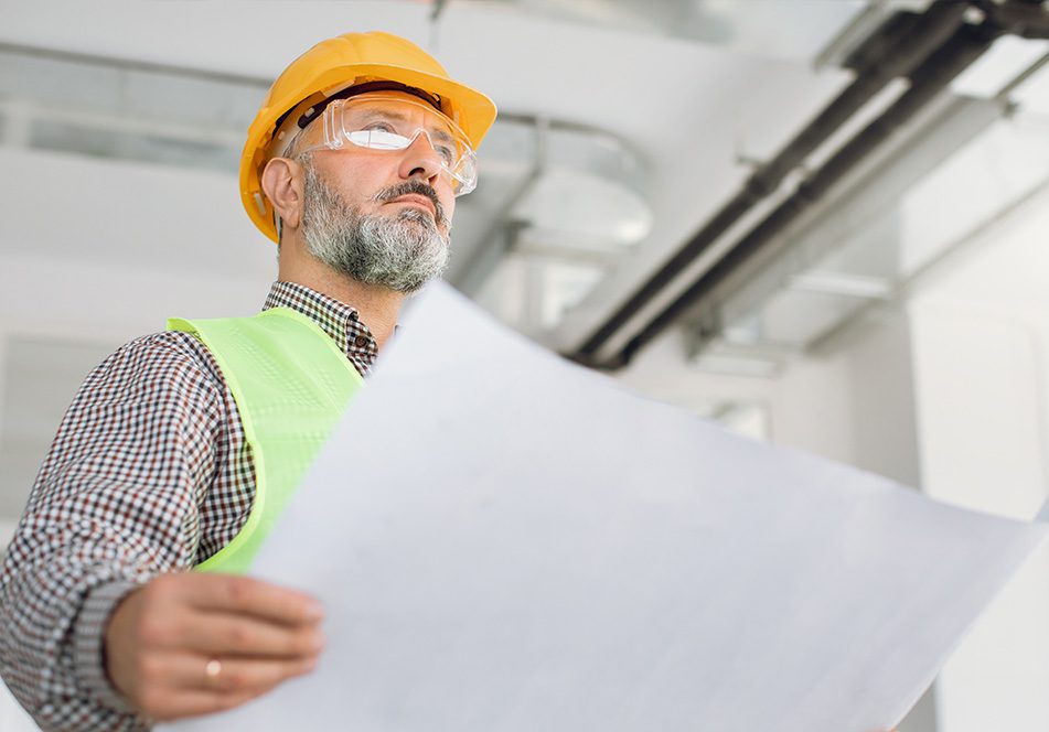 professional mature builder in special uniform holding blueprint