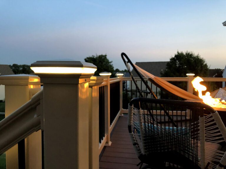 Outside deck lighting on a post cap with a hammock and fire pit in the background.