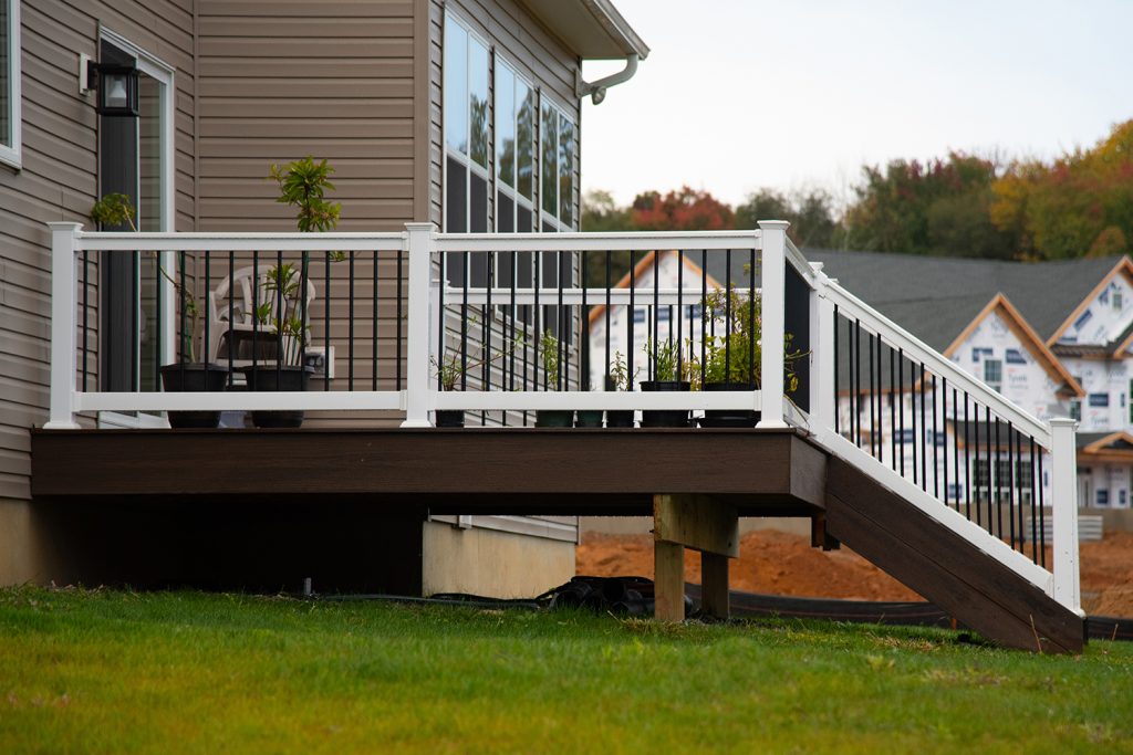 A view from the side of a dark brown deck with white vinyl railing.